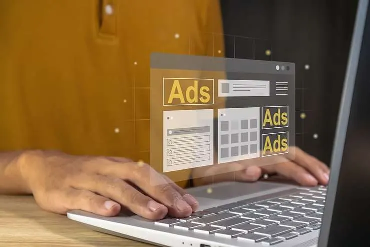 Hands on a laptop with floating digital ad screens